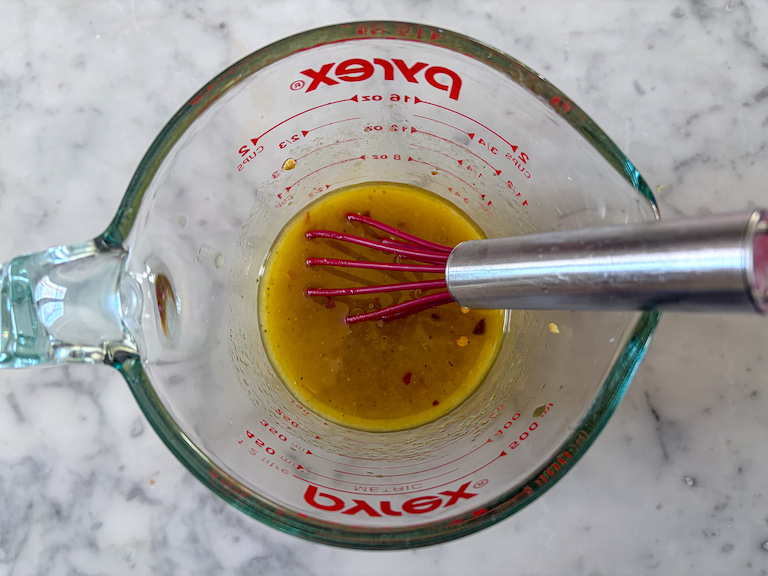 vinaigrette salad dressing in a measuring cup with a whisk