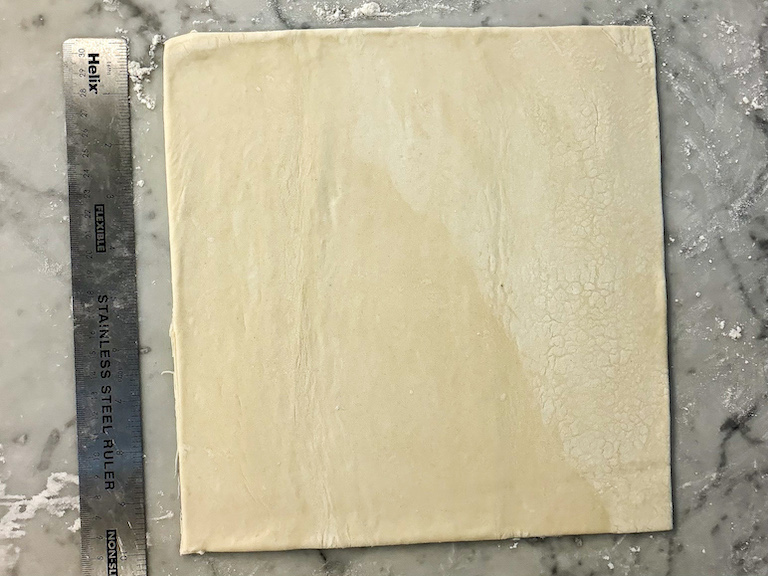 square of puff pastry on a marble surface with a ruler
