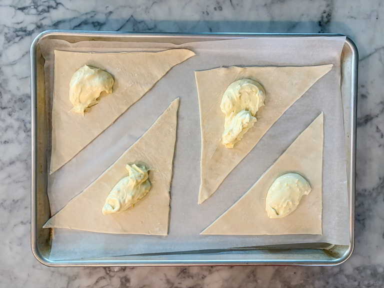 triangles of puff pastry with spoonfuls of cheese in the middle