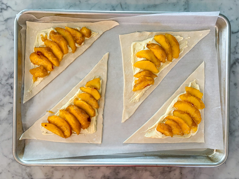 triangles of puff pastry with cheese and peach slices arranged on top