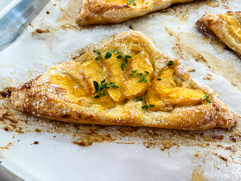 Puff pastry triangle with cheese, peach slices, honey, and thyme