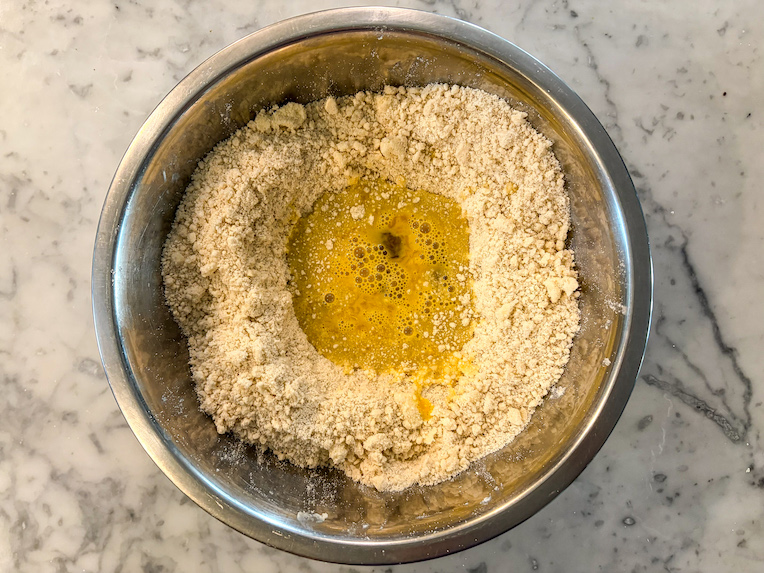 beaten eggs in bowl of dry shortcrust pastry ingredients