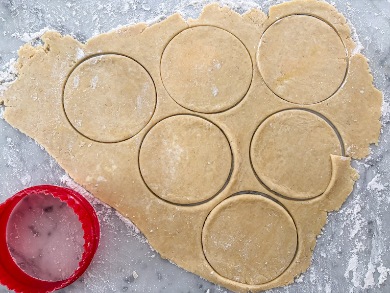 cutter cutting discs of pastry on a marble surface