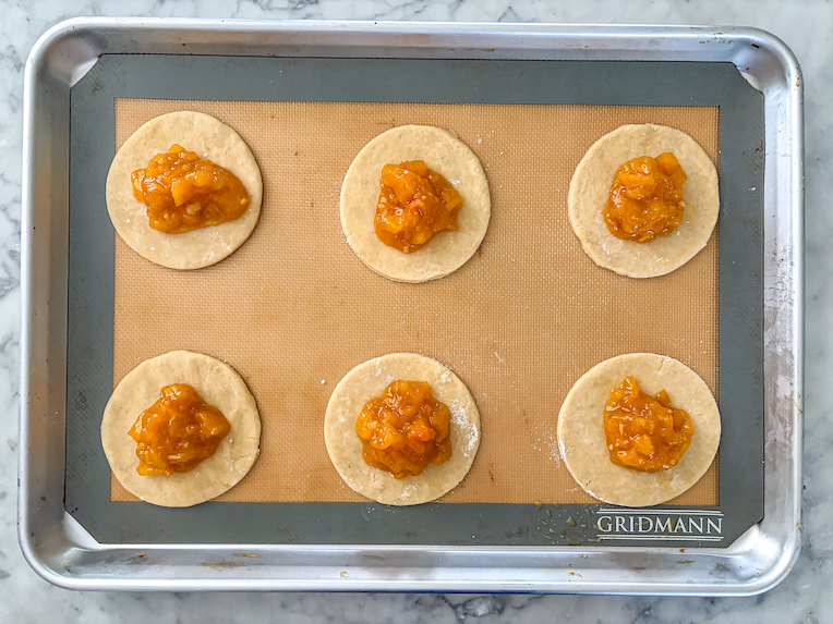 discs of shortcrust pastry on a tray with peach jam