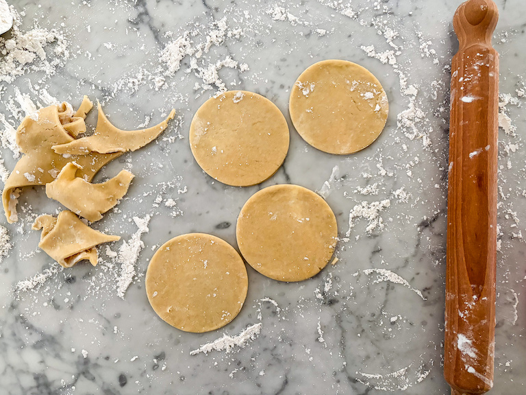 rolling pin on floured countertop with discs of pastry