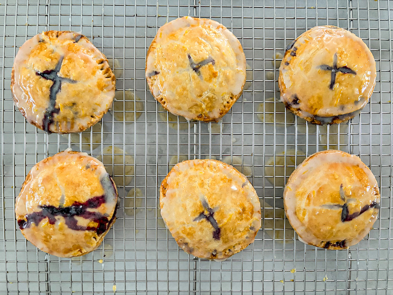 six glazed blueberry hand pies on a wire rack