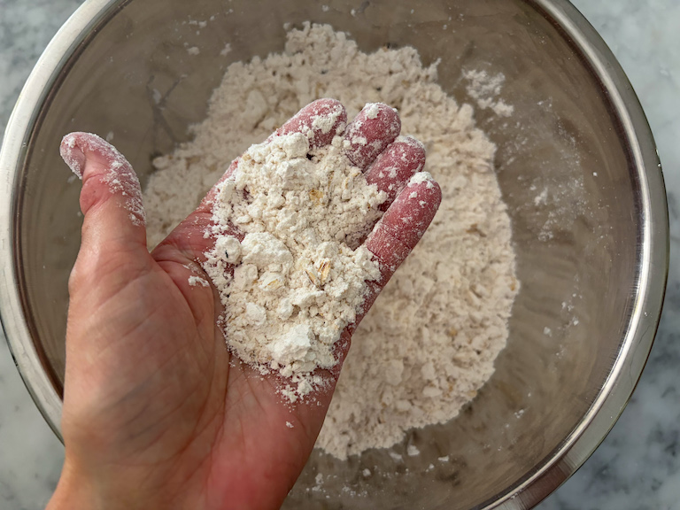 hand holding crumbled flour, oat, and butter mixture