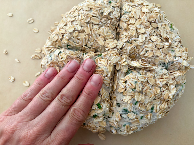 hand pressing down the opening of a loaf of soda bread, before baking
