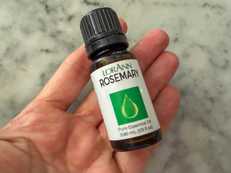 hand holding a bottle of rosemary oil
