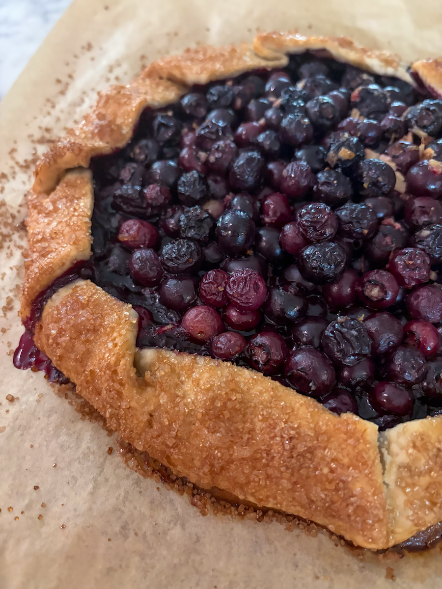 closeup vertical shot of a blueberry galette on a sheet of parchment after baking