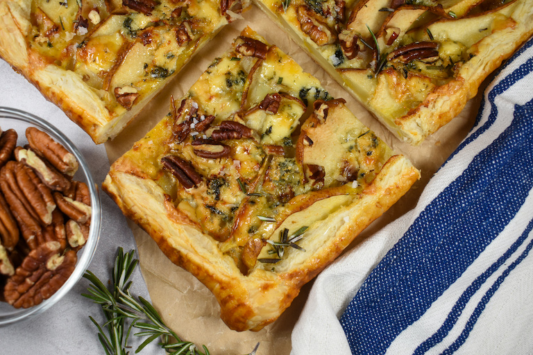 sliced pear and blue cheese tart with a blue striped towel