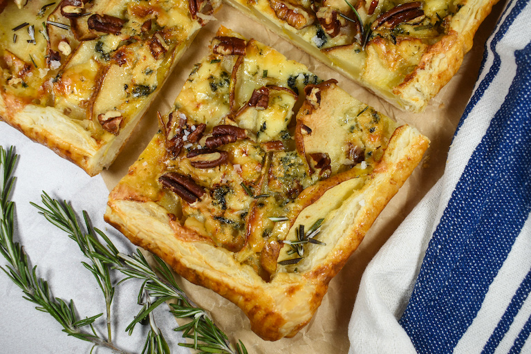 slices of pear tart and sprigs of rosemary with a blue striped towel