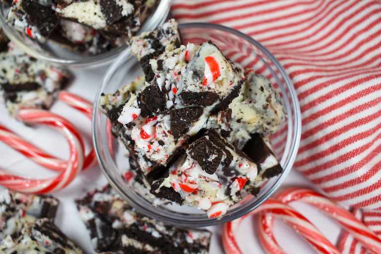 a dish of peppermint bark surrounded by candy canes and a red striped towel