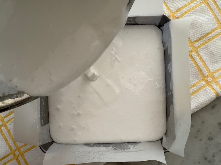 pouring marshmallow fluff into a square tin