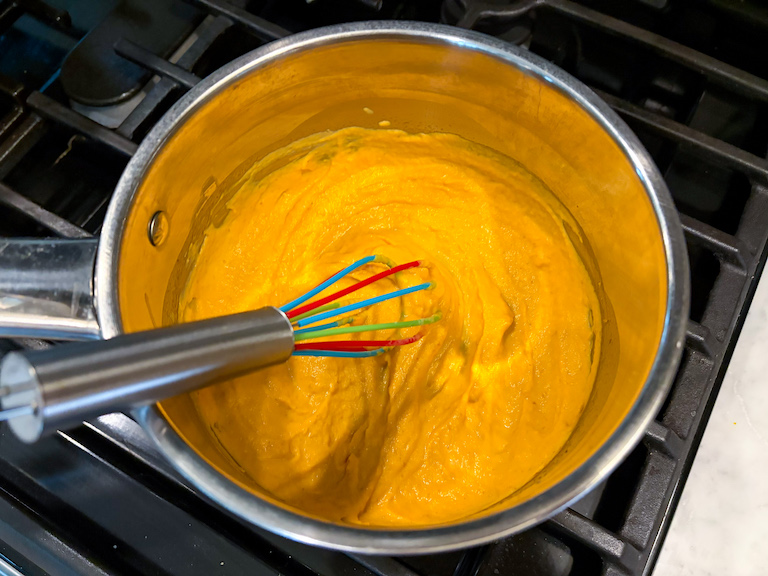 pumpkin puree and cream in a pan with a whisk