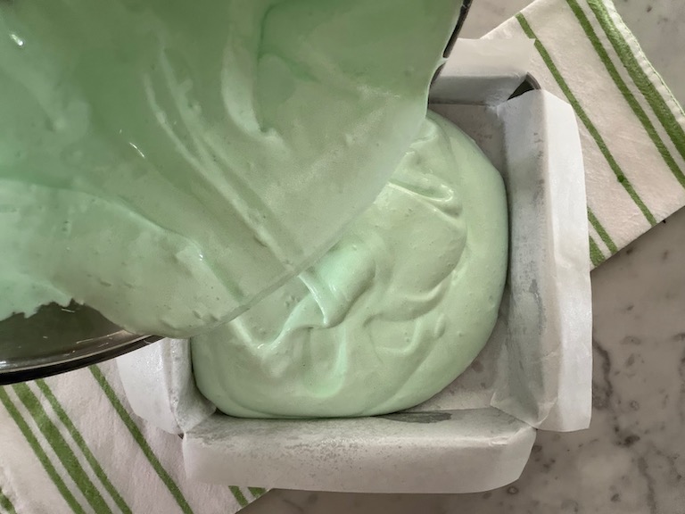 pouring marshmallow fluff into a lined tin
