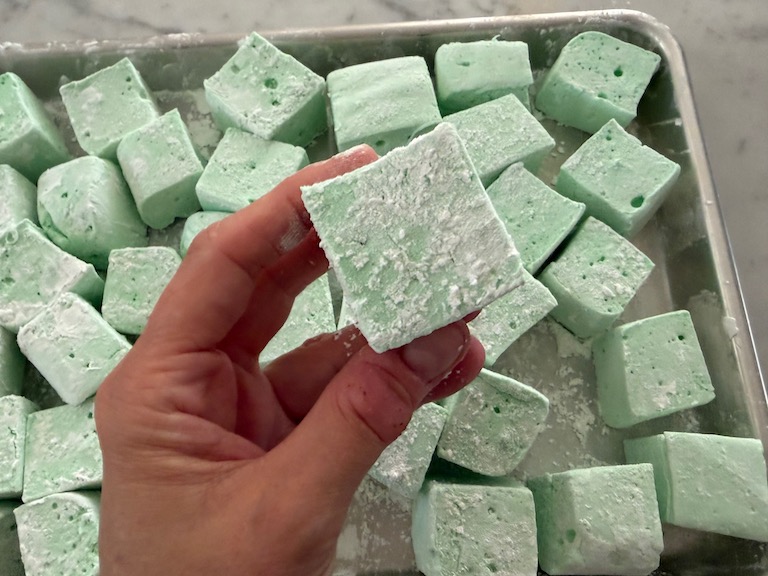 hand squeezing a mint marshmallow