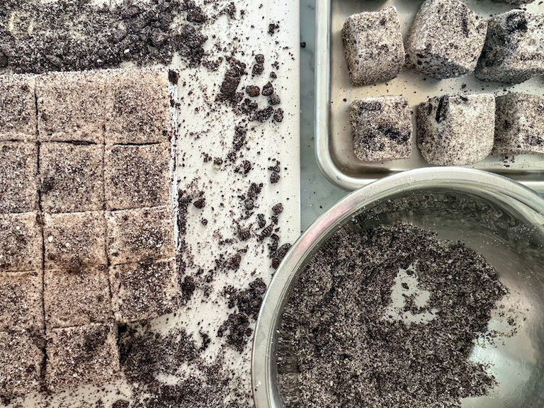 coating cookies and cream marshmallows in Oreo powder