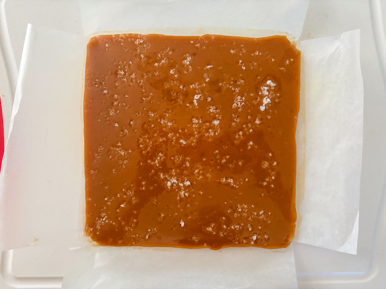 a slab of caramel on a cutting board with a sheet of parchment underneath