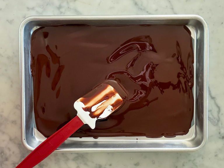 dark chocolate spread on a metal tray with a spatula