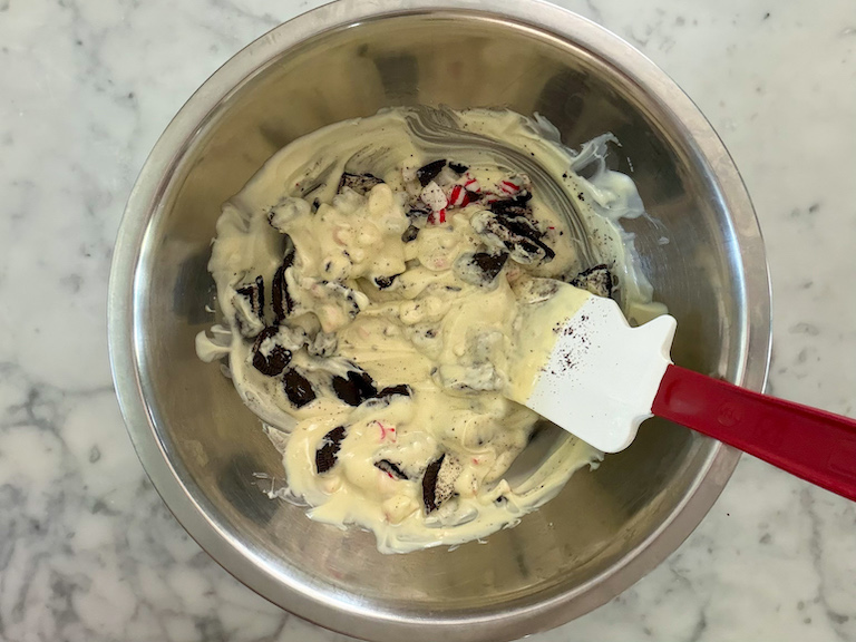 stirring melted white chocolate and oreos in a metal bowl