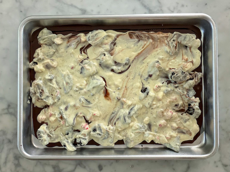 white chocolate with oreos and peppermint spread across a metal tray