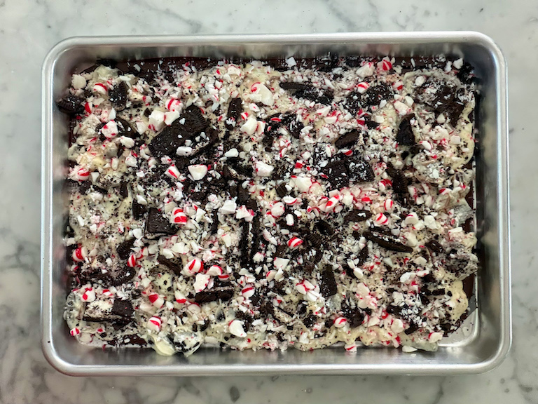 peppermint bark with oreos and candy canes cooling on a tray