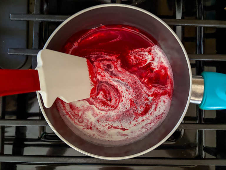 stirring raspberry puree and cream in a saucepan