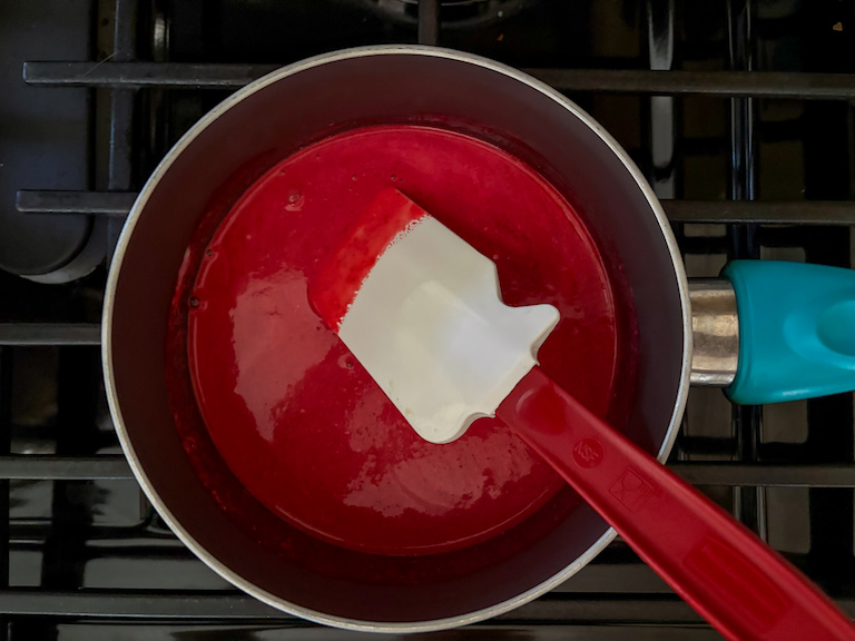 raspberries and cream in a saucepan with a spatula