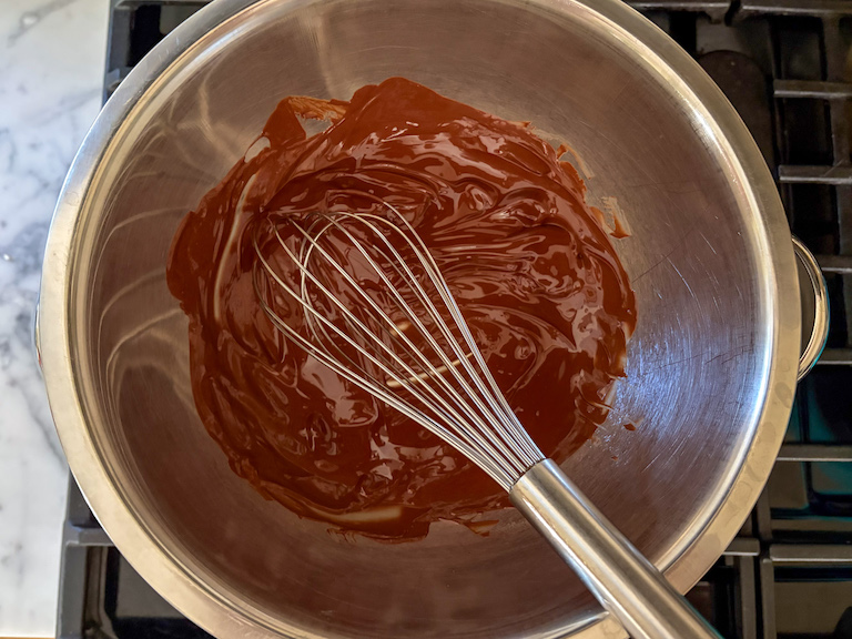 melted chocolate in a bowl with a whisk