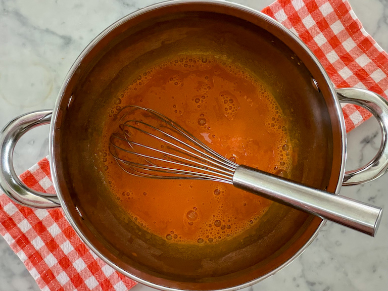 whisking carrot juice in a pot