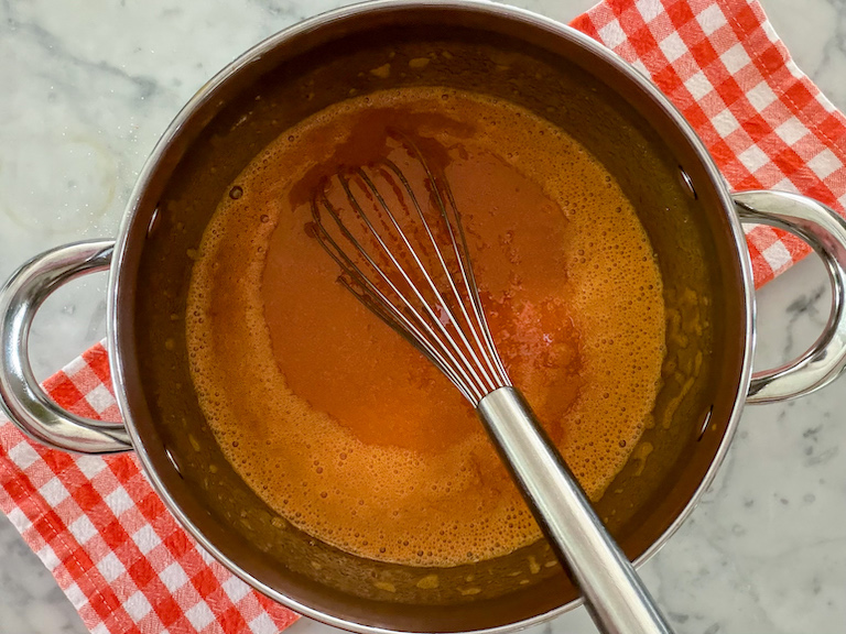 pot of carrot juice with a whisk