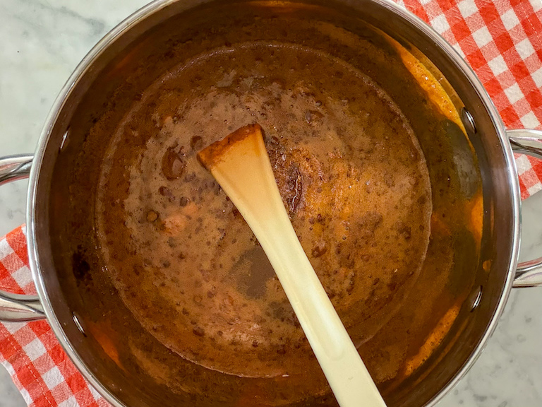 a pot of carrot candy syrup with a spoon