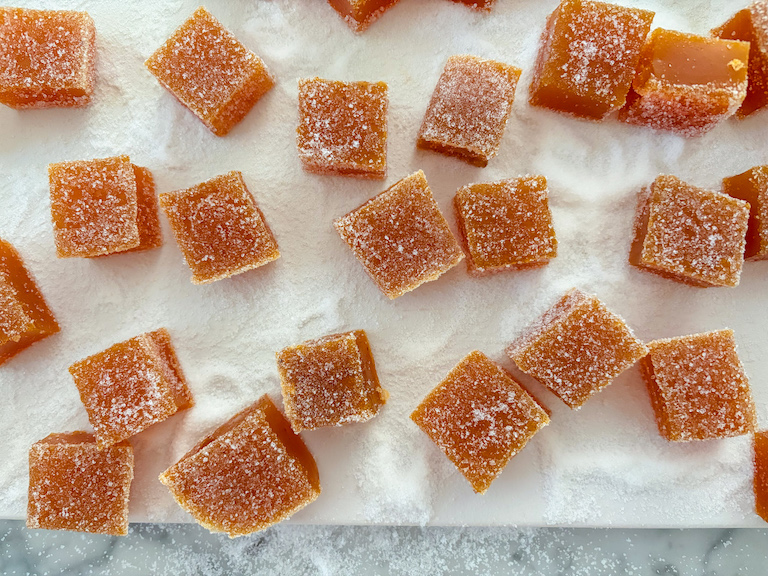 squares of orange carrot candy on a white cutting board