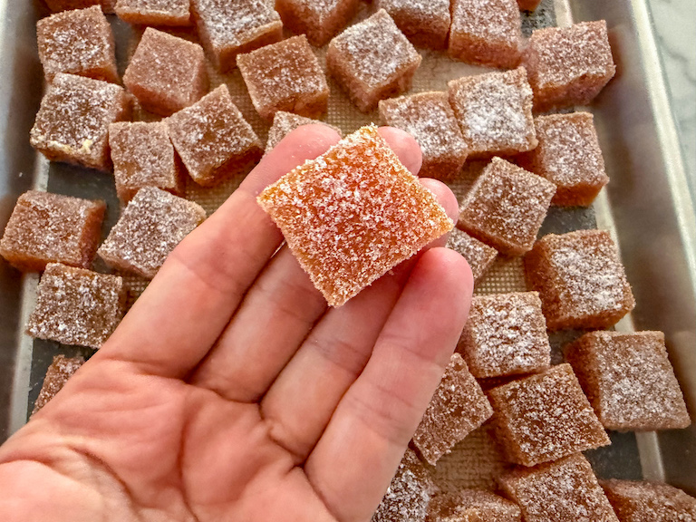 hand holding a square of carrot candy