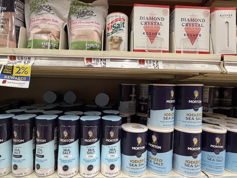 canisters and boxes of salt lining a supermarket shelf