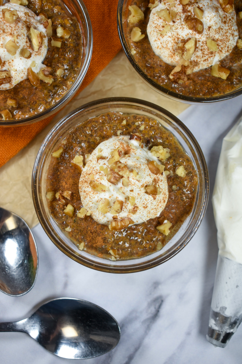 dishes of chia pumpkin pudding garnished with nuts and whipped cream