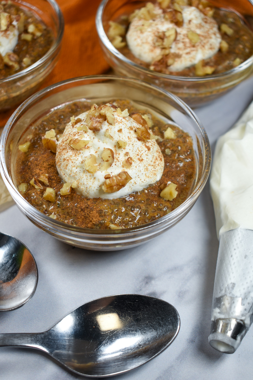 dishes of chia pumpkin pudding with nuts and whipped cream on top
