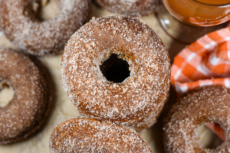 apple cider donuts stacked on a sheet of brown parchment