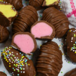 buttercream eggs sliced in half to reveal pink and yellow centers