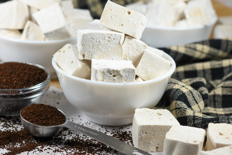 a bowl of coffee marshmallows and spoonful of ground coffee