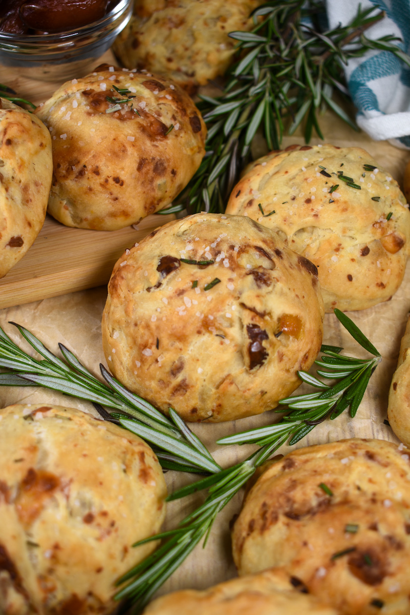 dinner rolls and rosemary sprigs on a parchment surface