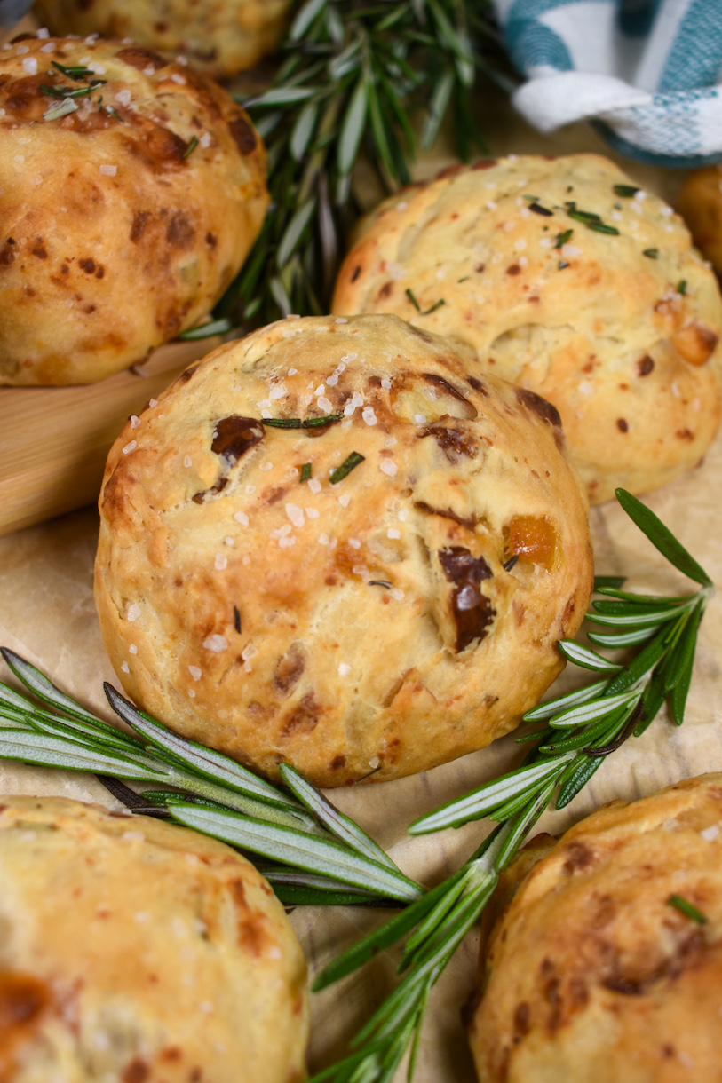 date and blue cheese dinner rolls and rosemary sprigs on a sheet of parchment