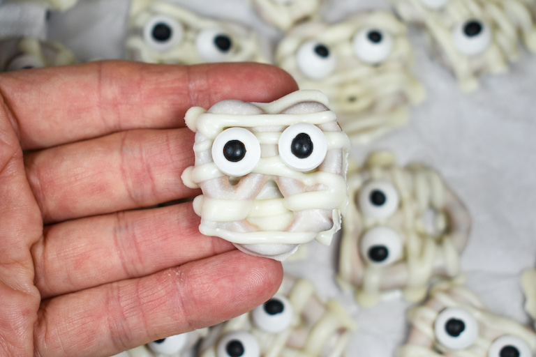 hand holding a white chocolate mummy pretzel