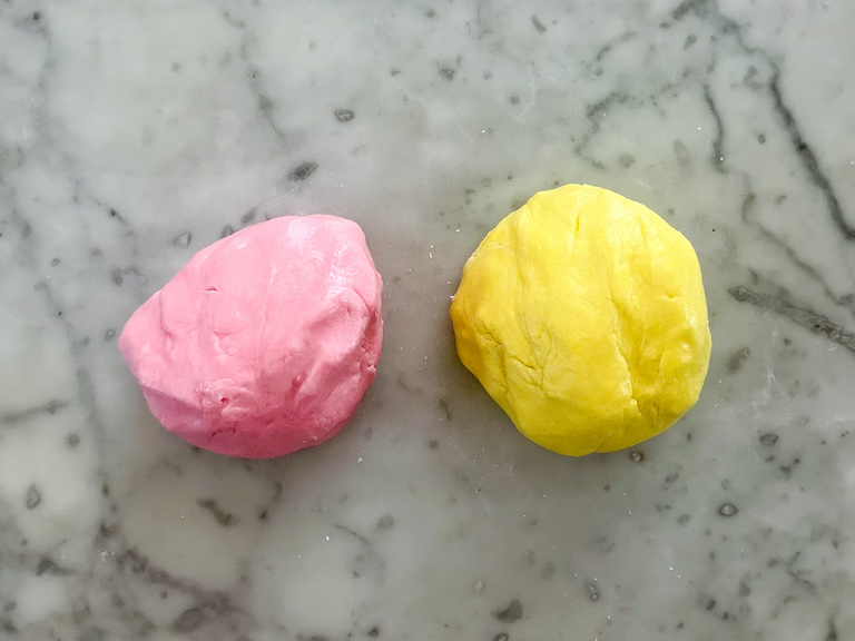 balls of pink and yellow buttercream on a marble surface