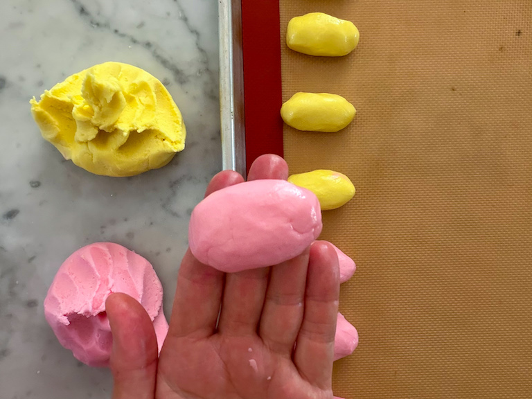 hand shaping pink buttercream into an egg shape