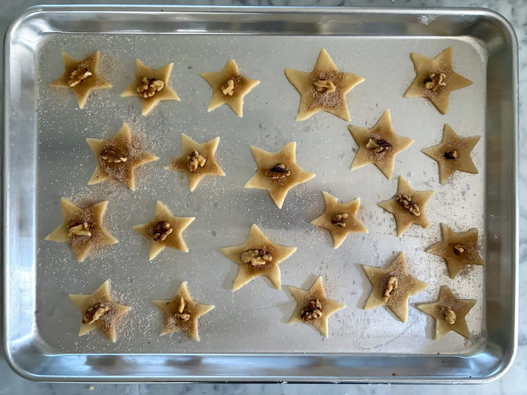 a tray of sand tart cookies decorated with nuts and cinnamon sugar
