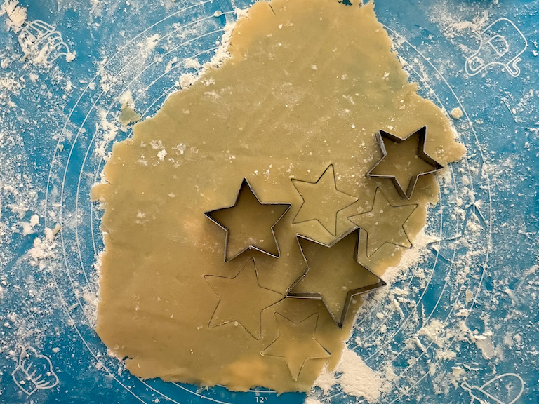 cutting star shapes of cookie dough with a metal cutter