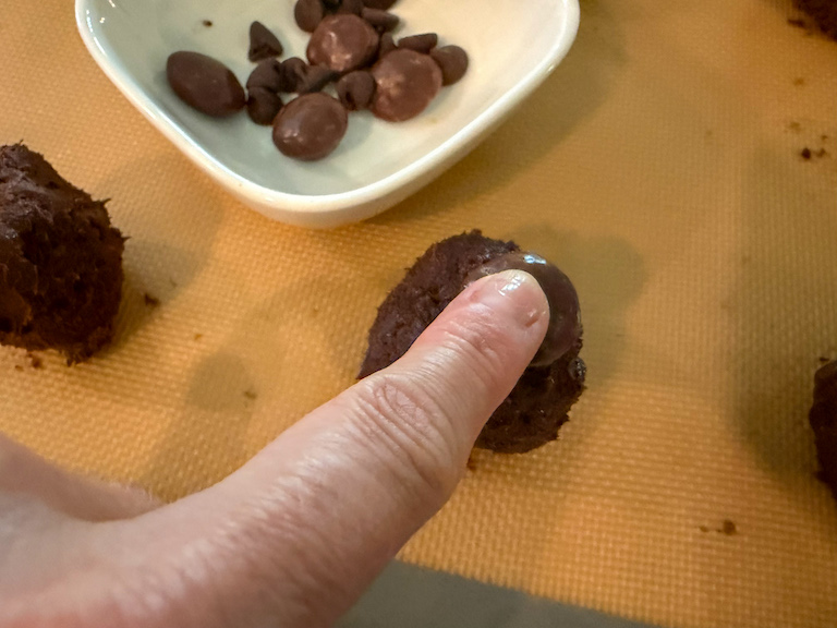 pressing milk duds into chocolate cookie dough