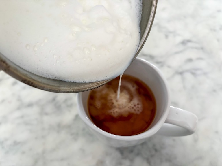 adding steamed milk to tea
